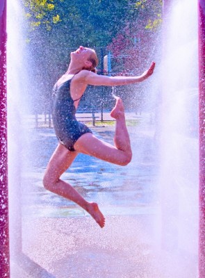 Photo of a dancer splashing through a spray park water fountain