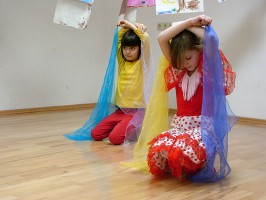 IMAGE Two girls in a dance class site and hold scarves over their heads IMAGE
