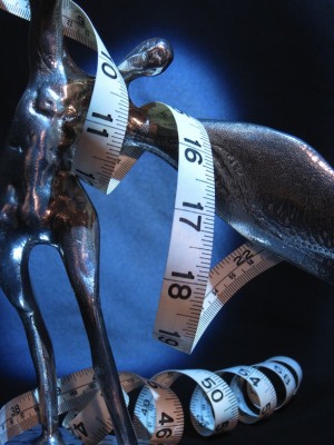 IMAGE Measuring tape winds around a statue of a figure bending sideways like a dancer. IMAGE