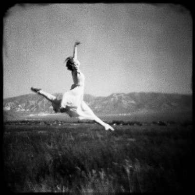 Dancer frolicking in the grass with a mountain in the background