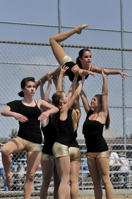 Photo of four dancers lifting another overhead as if in flight
