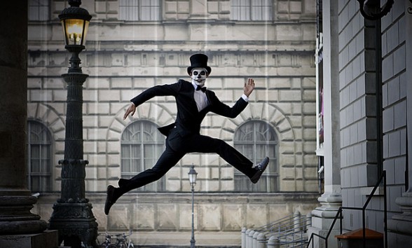 A dapper skeleton-faced man leaps across a street in Munich