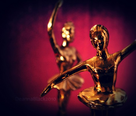 Two dance trophies against a deep pink backdrop