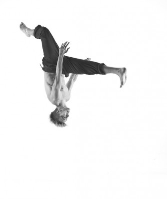 A black and white photo capture of a male dancer mid-flip, upside-down