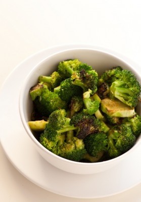 A white bowl contains broccoli and vegetables