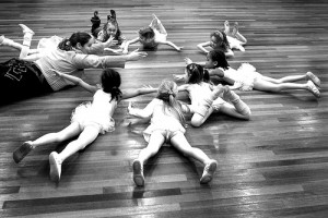 IMAGE Young dancers lying on their tummies in a circle with their teacher. IMAGE
