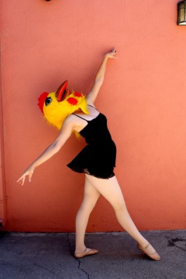 IMAGE The Adult Beginner poses in front of an orange wall wearing a large chicken head. IMAGE
