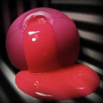 IMAGE A pink, broken stress ball oozes a thick pink liquid over a black and white surface. IMAGE