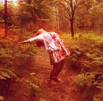 IMAGE A girl arcs her body backward in a sepia-toned outdoor setting. IMAGE