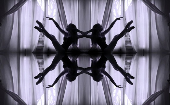 IMAGE A ballet dancer balances on her pelvis against a veiled window. On a reflective surface with a reversed image, there appears to be four of her. IMAGE