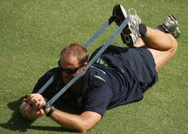 IMAGE A man lies on the ground, knee bent, exercising with a resistance band IMAGE