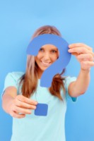 IMAGE A girl in a blue shirt holds a blue question mark. IMAGE