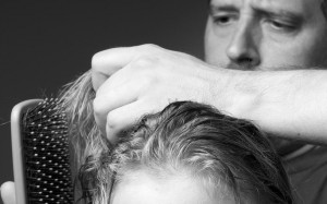 A father brushes the tangles from his daughter's damp hair