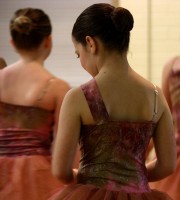 Ballet students in rust-colored costumes wait in the studio