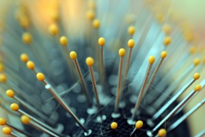 Macro view of a hair brush with metal bristles tipped with bright yellow plastic