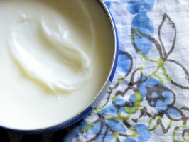 A tin of white hair putty sits on blue and white flowered gossamer fabric.